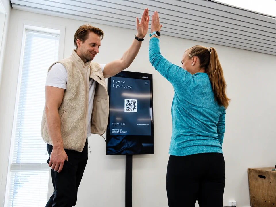 En trener og et medlem gir hverandre en high-five.