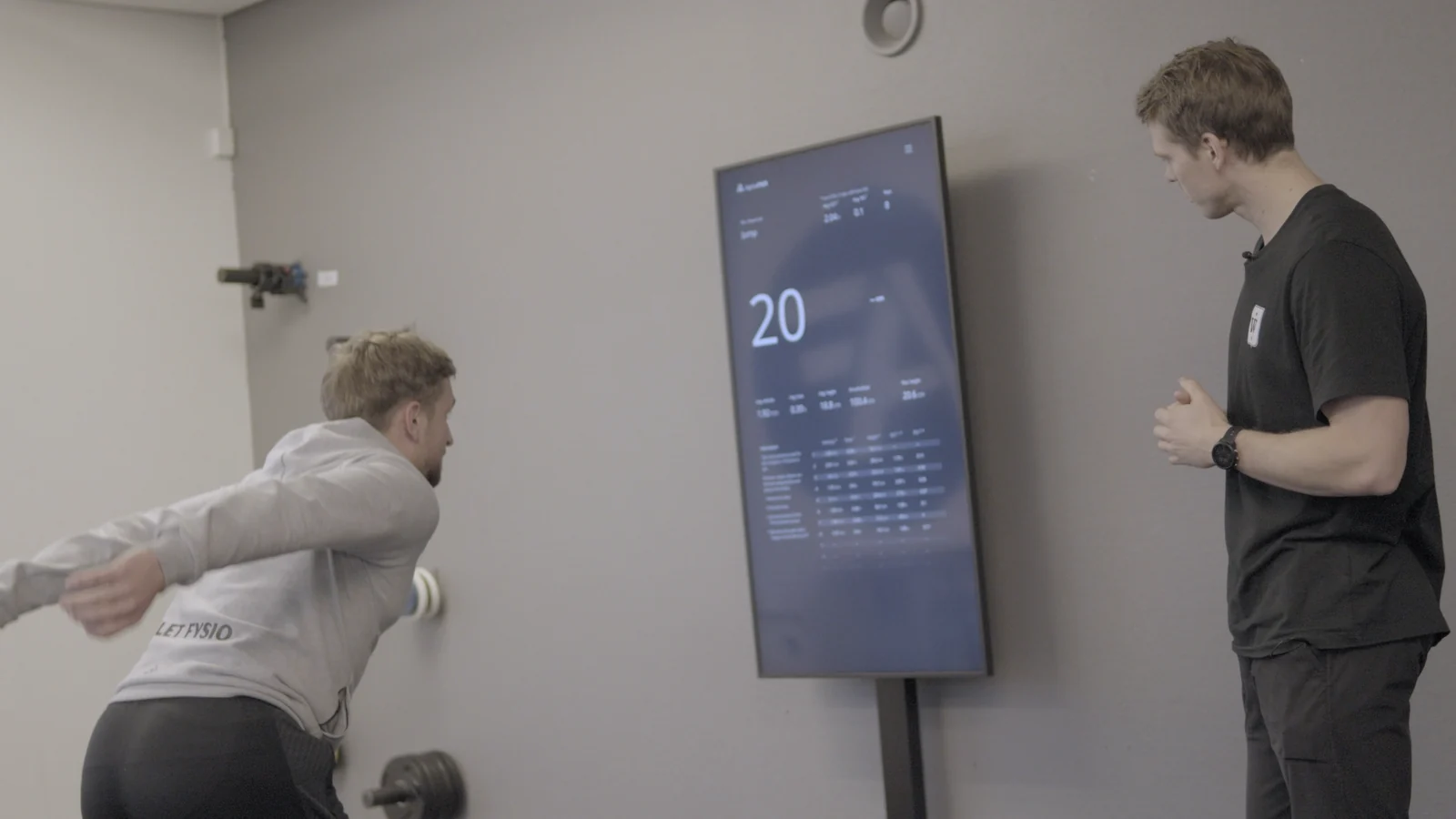 En bruker gjennomfører en test foran Alphatek-skjermen mens en veileder følger med.