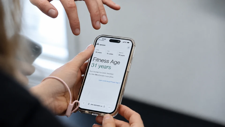 Et medlem og en trener går gjennom Fitness Age-resultater på telefonen.